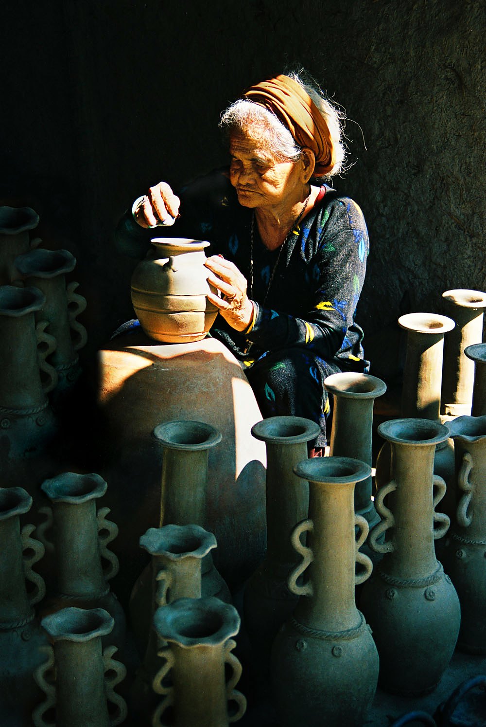 Người thợ nữ cao tuổi đứng dưới vệt nắng giữa những bình mộc